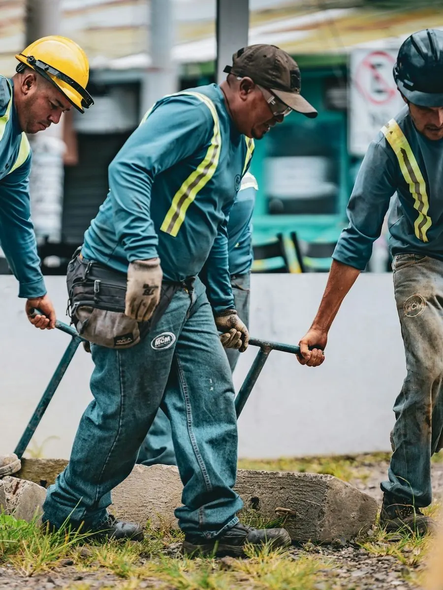 Three workers moving a concrete form together at a street job